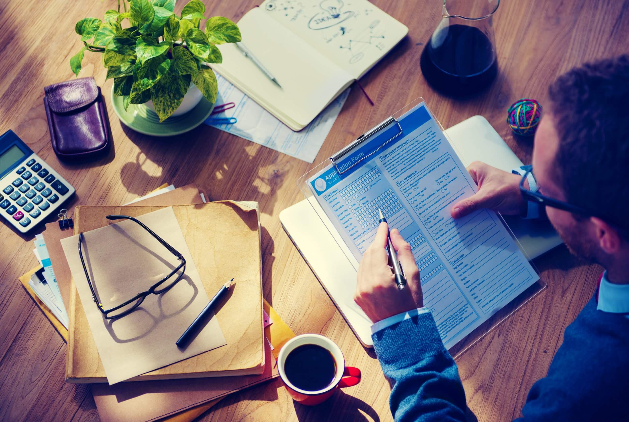 Man Casually Filing In The Application Form On His Wooden Desk