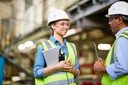 Technician inspecting a young trainee at factory