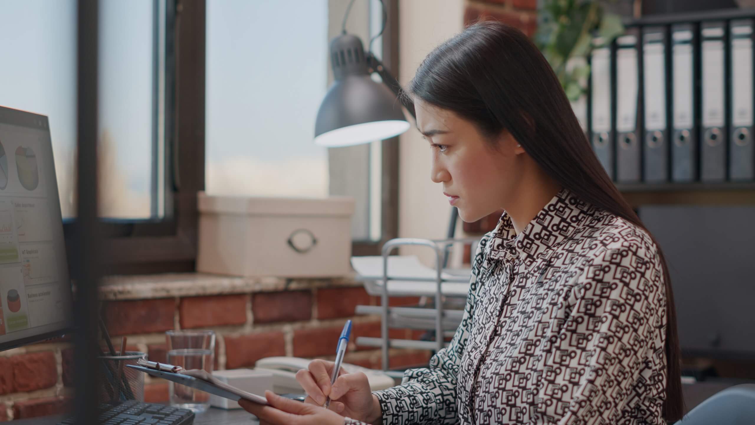 Business woman looking at files on clipboard to work on strategy in company space. Employee analyzing data charts on papers to plan financial project, working on startup development.