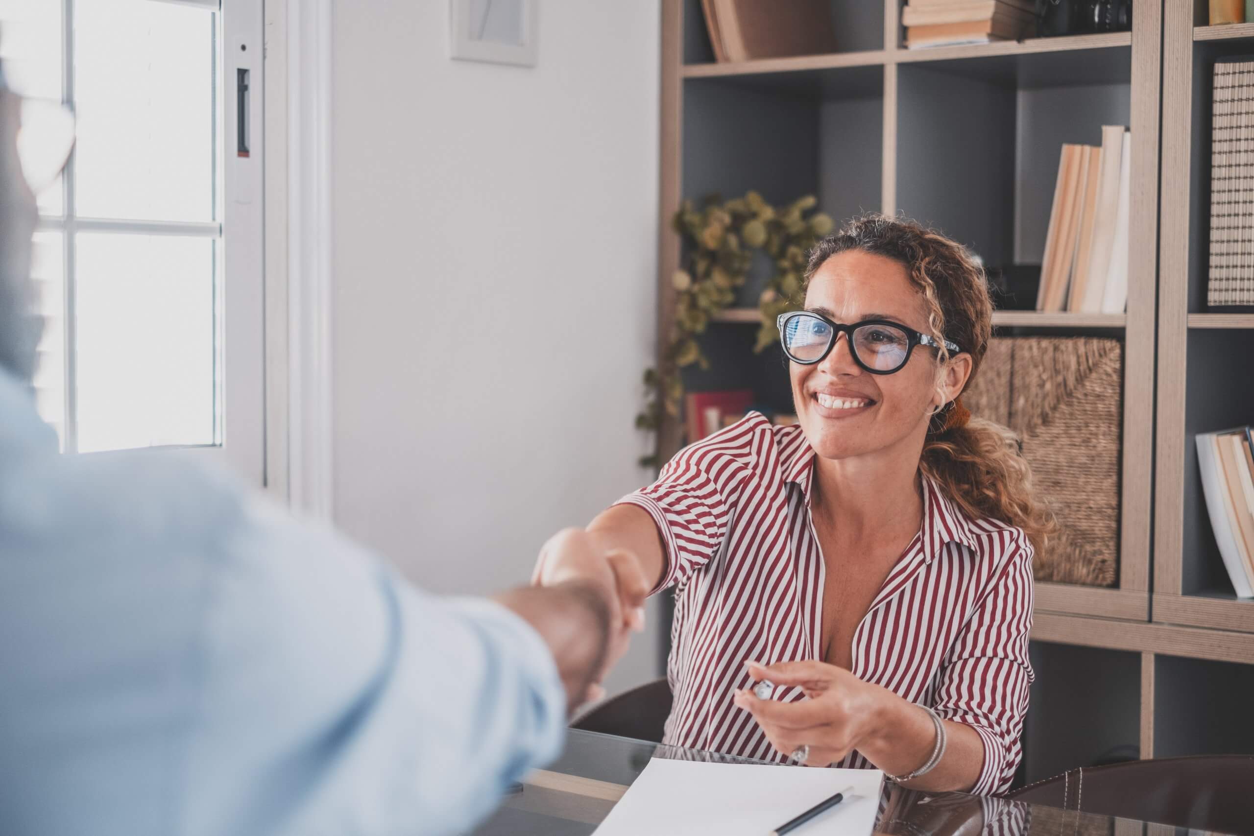 Smiling caucasian female hr manager handshake hire male candidate at job interview make good first impression, happy mixed race client shake hand of bank broker, respect, business agreement concept